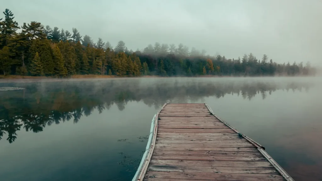 A long wooden dock reaching into a misty lake at dawn