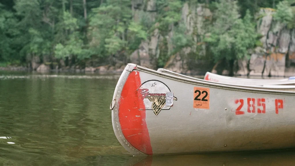 A canoe drawn up on the rocky shore of a northern forest lake