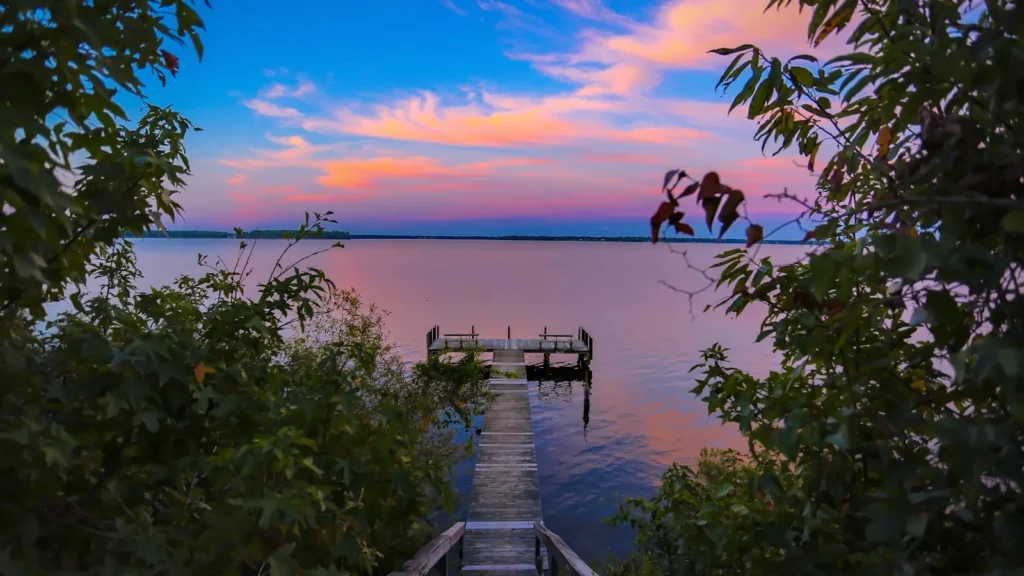 A dock reaching out over wide brackish water at dusk