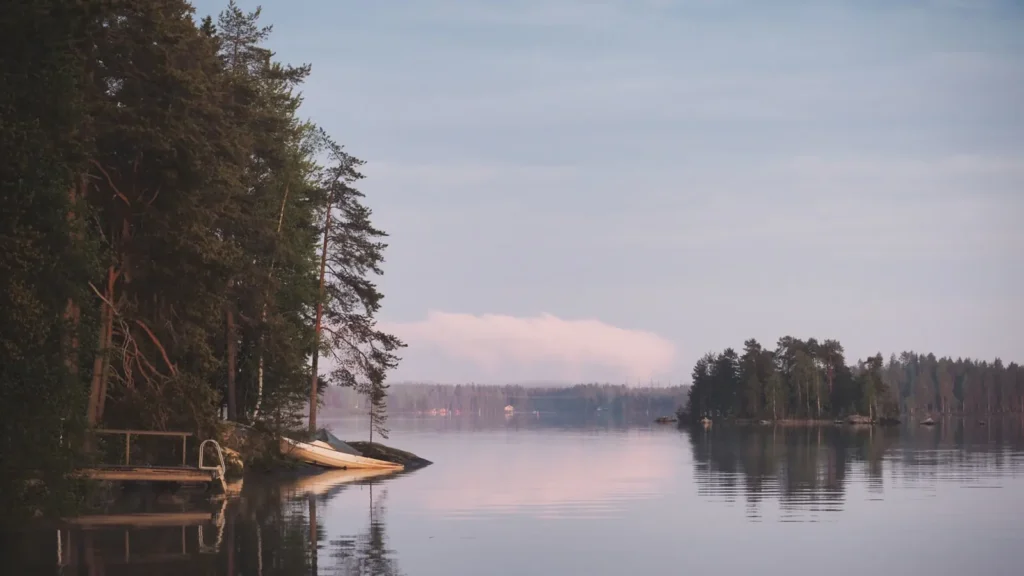 A quiet lake ringed by trees under a clouded sky