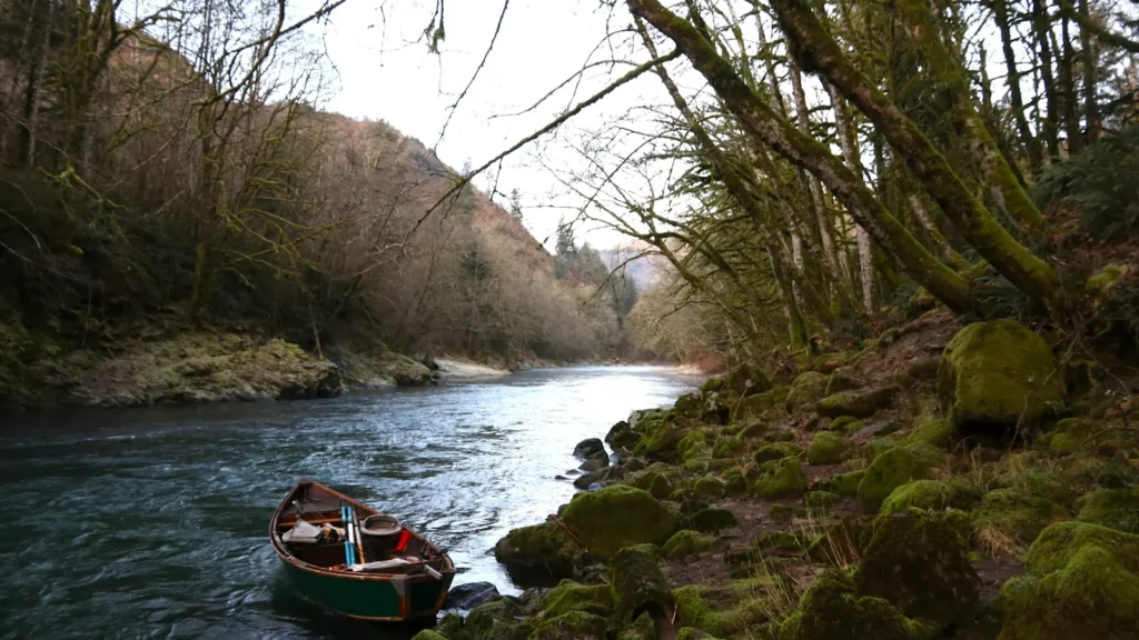 A red drift boat on a moss-lined river in the Pacific Northwest