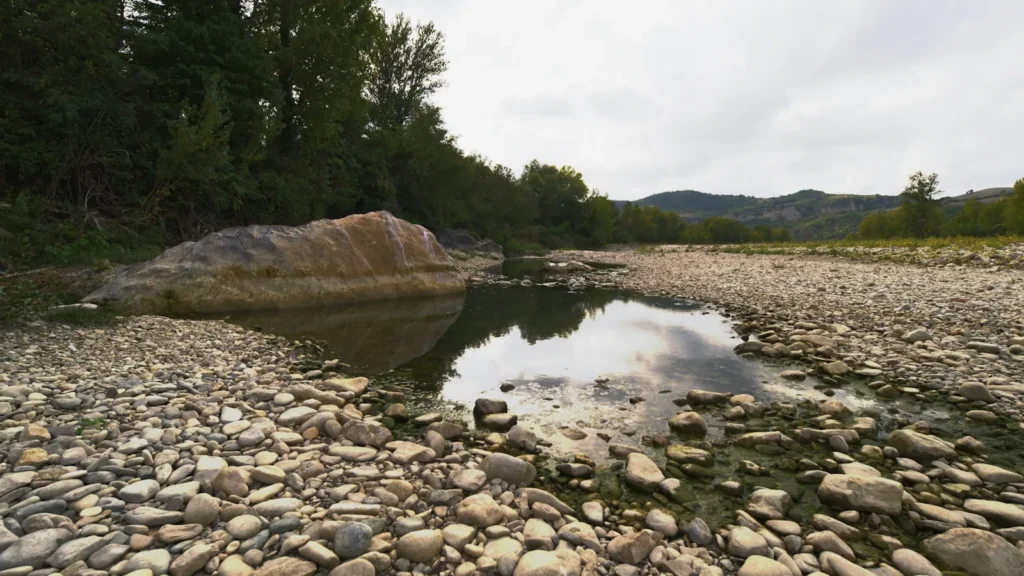 A boulder standing mid-channel in a shallow gravel river