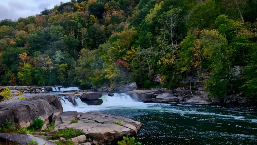 A river breaking over ledge rock between forested banks in the Appalachians