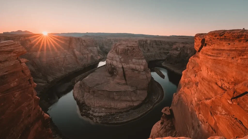 Sun setting over a desert canyon cut by a river