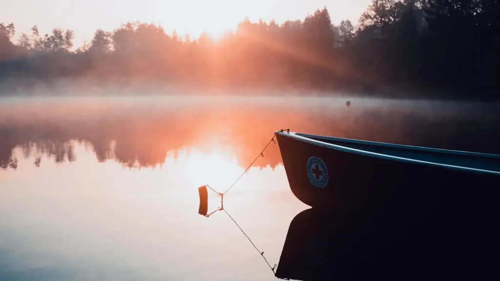 The bow of a boat on flat reservoir water in early light