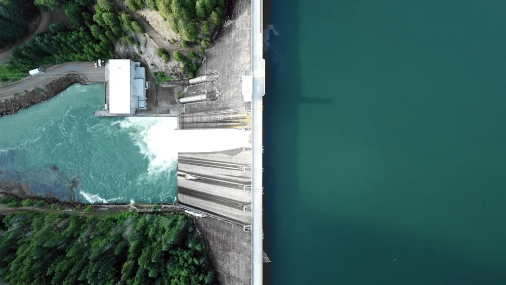 A concrete dam releasing water into the river below it
